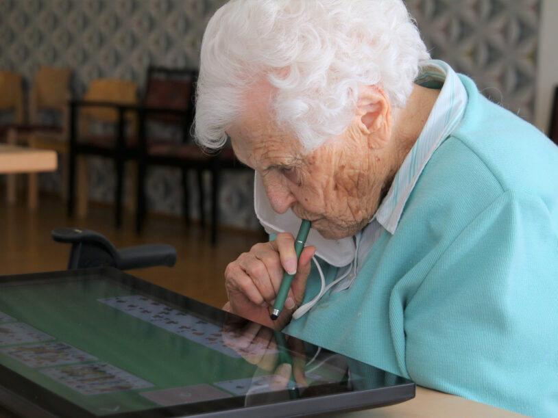 Ältere Frau grübelt über einer digitalen Patience