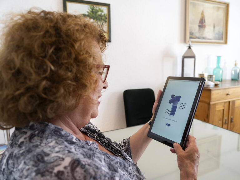 Ältere Frau schaut auf ein Tablet auf dem steht, was ist künstliche Intelligenz