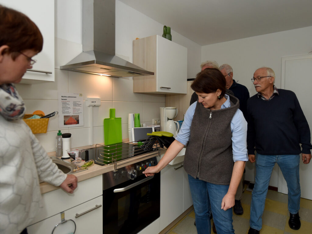 Eine Frau demonstriert eine automatische Herdabschaltung in einer Musterküche.