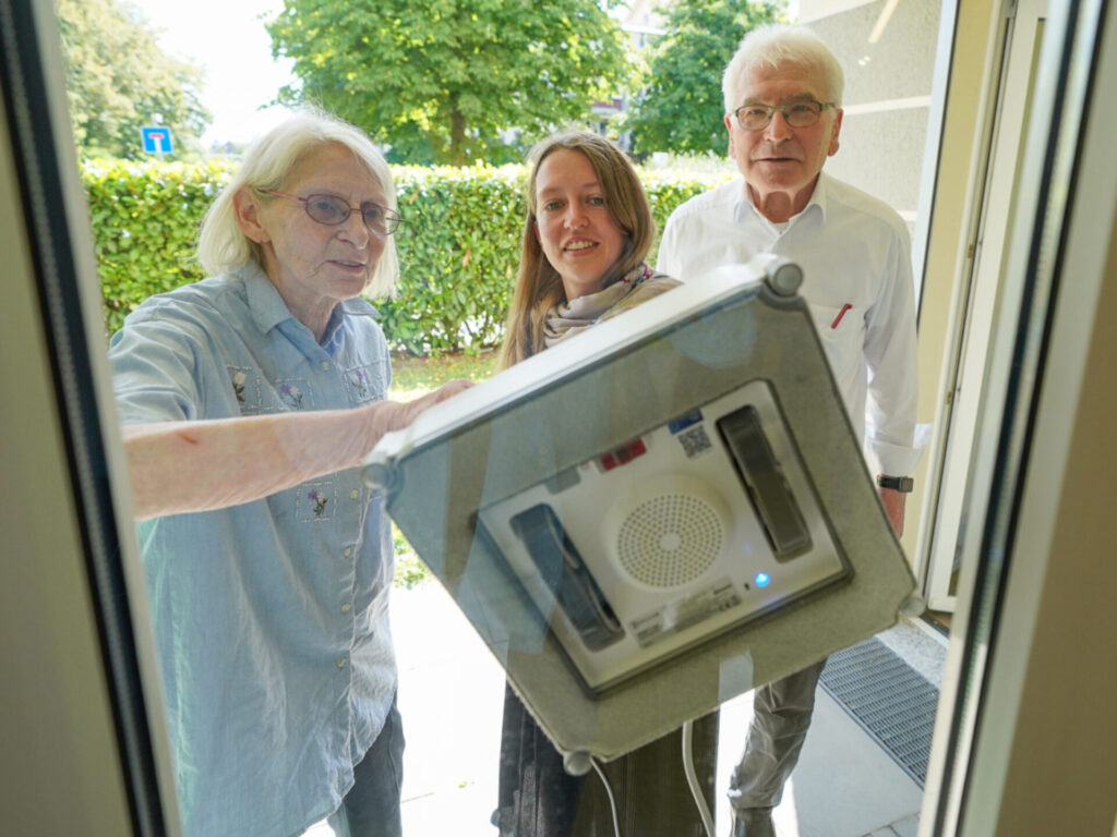 3 Personen testen einen Fensterputzroboter