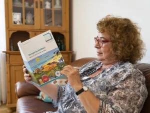 Frau liest eine Broschüre mit dem Titel "Neugierig bleiben. Lernen und Bildung im Alter"