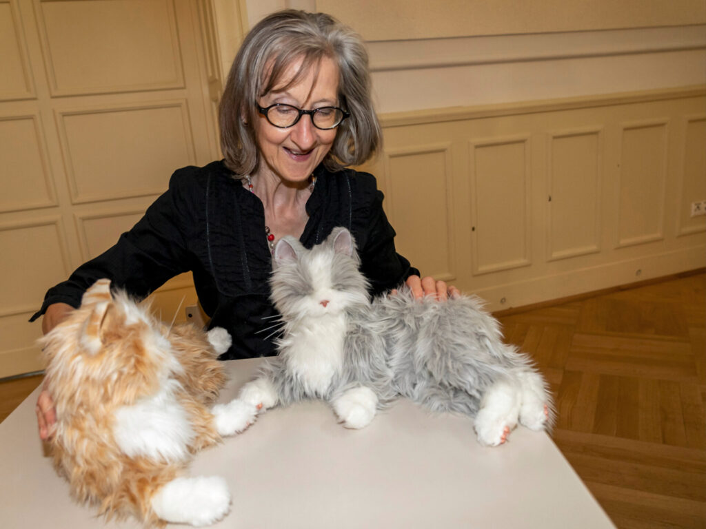Frau streichelt zwei Roboterkatzen