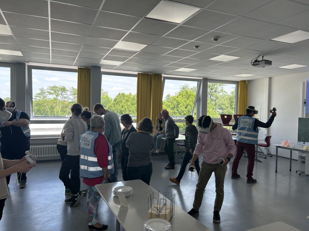 Mehrere ältere Menschen und Schülerinnen und Schüler probieren VR Brillen aus