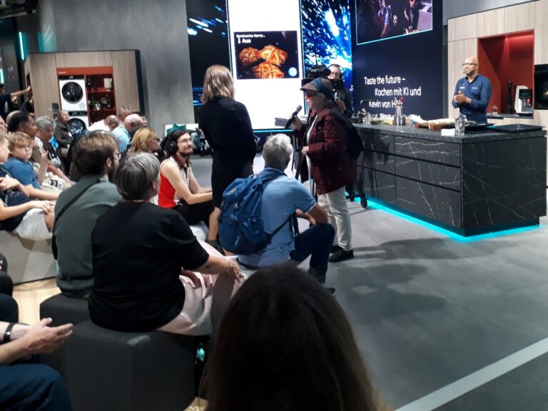 Frau Beutelhoff vom dvbs spricht zum Publikum der Kochshow "Kochen mit KI" bei der IFA 2024