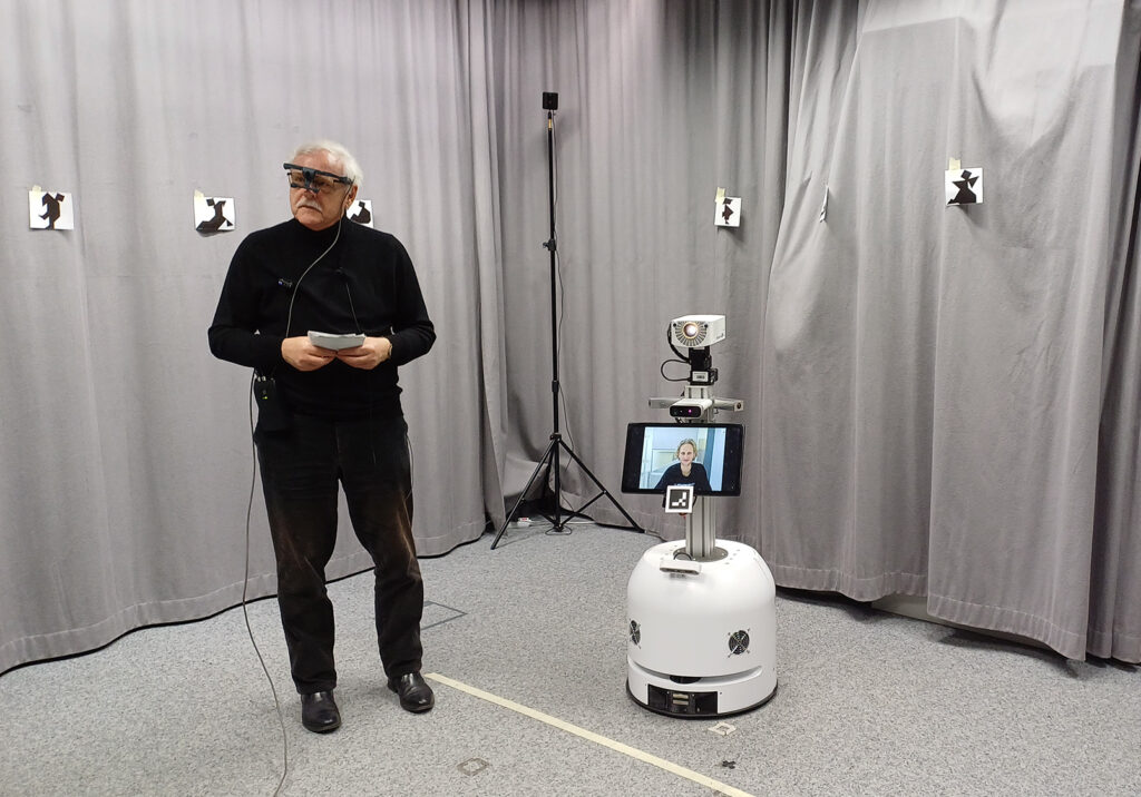 Älterer Mann in Raum mit Vorhängen und Roboter mit Bildschirm
