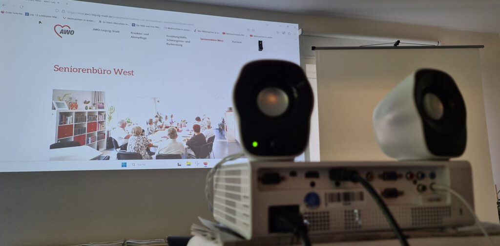 ein Beamer wirft ein Bild der Website des Seniorenbüro West der AWO an eine Wand