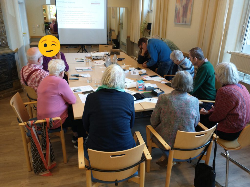eineGruppe älterer Menschen sitzt um einen Tisch herum