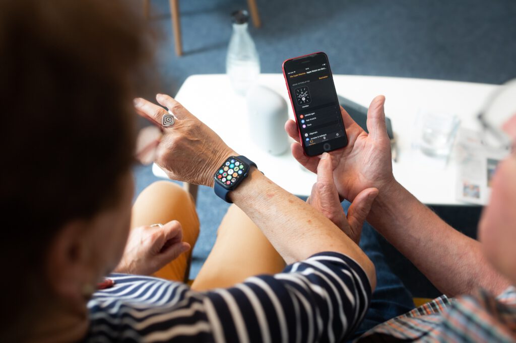 ein Arm mit einer Smartwatch wird neben ein Smartphone gehalten